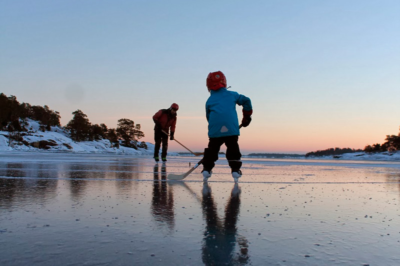 Två barn spelar ishockey på isen på en sjö