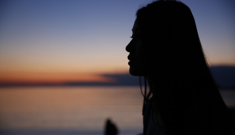 Kvinna i mörker tittar ut över havet