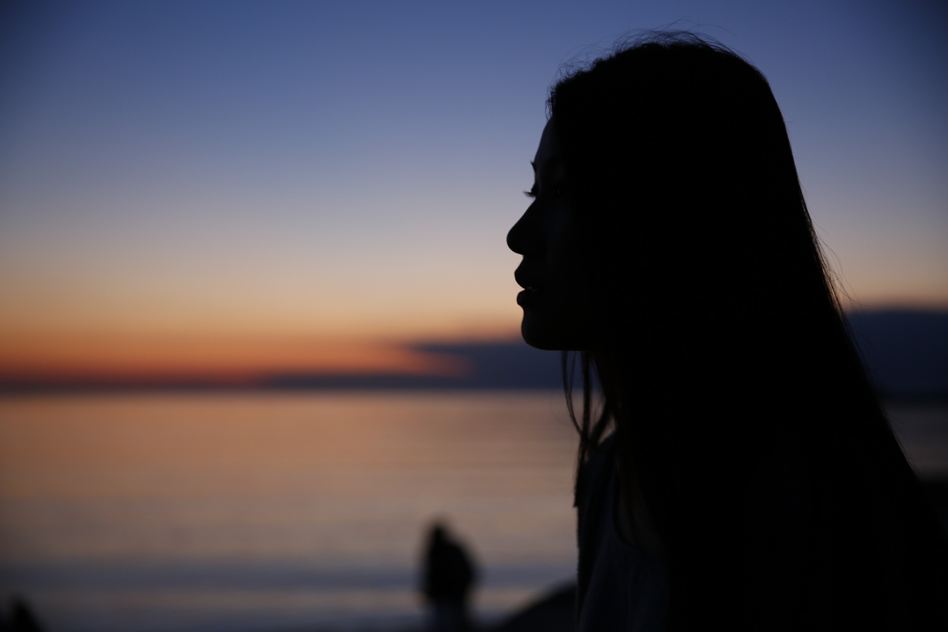 Kvinna i mörker tittar ut över havet